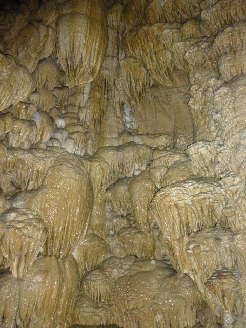 Inner view of a cave showcasing unique, textured rock formations resembling dripping icicles.