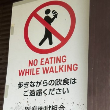 Sign indicating 'No Eating While Walking' in English and Japanese.