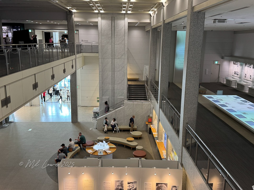 Interior view of the Hiroshima Peace Memorial Museum, showing seating areas and exhibits, with visitors engaging with the displays.