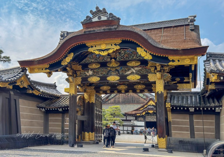 A grand entrance gate of Nijo Castle in Kyoto, Japan, showcasing intricate gold detailing and traditional Japanese architecture.