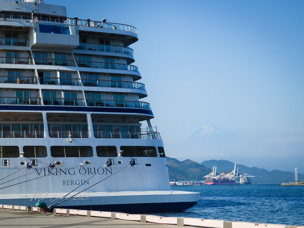 The Viking Orion cruise ship docked at a port with views of Mount Fuji in the background on a clear day.