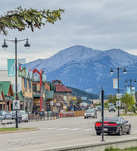 Street view of a town in the Canadian Rockies, featuring shops and restaurants with mountains in the background.