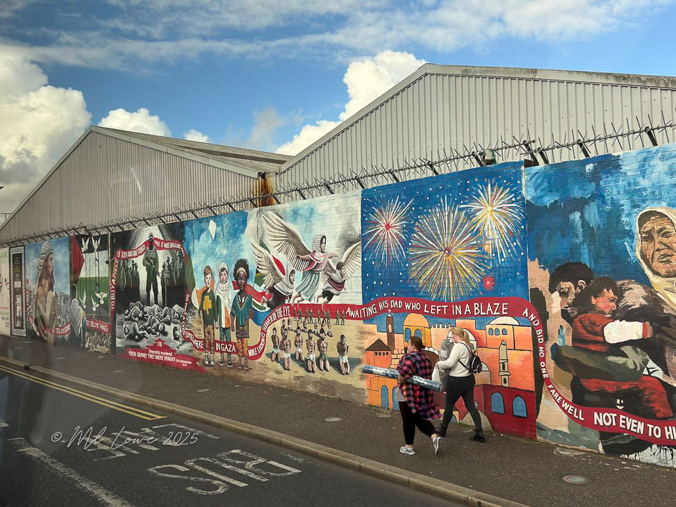 A vibrant mural depicting scenes of cultural and political significance in Belfast, Northern Ireland, featuring imagery related to various social issues and community stories, with people walking by.