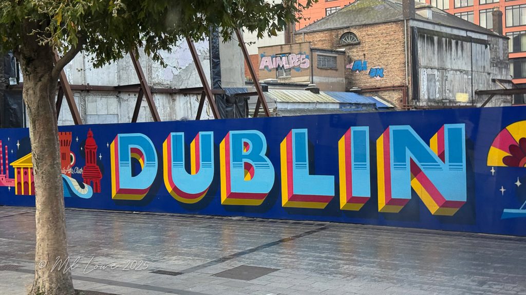 A vibrant mural featuring the word 'DUBLIN' in bold, colorful letters, with outlines of iconic Dublin landmarks in the background.