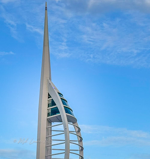 A close-up view of the Spinnaker Tower in Portsmouth, England, against a bright blue sky.