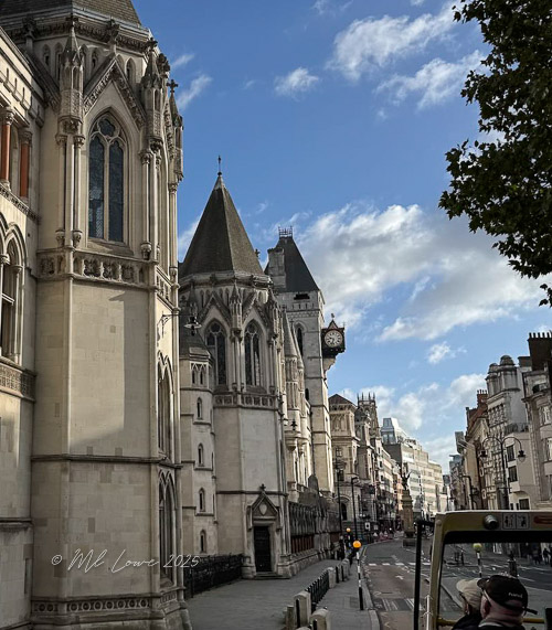 View of historic London architecture with intricate details under a blue sky with clouds.