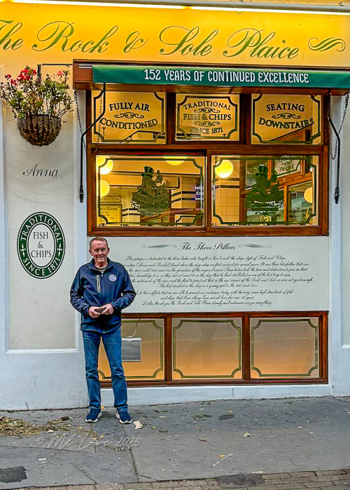 A man stands in front of The Rock & Sole Plaice, a traditional fish and chips shop in London, showcasing its iconic sign and historical details.