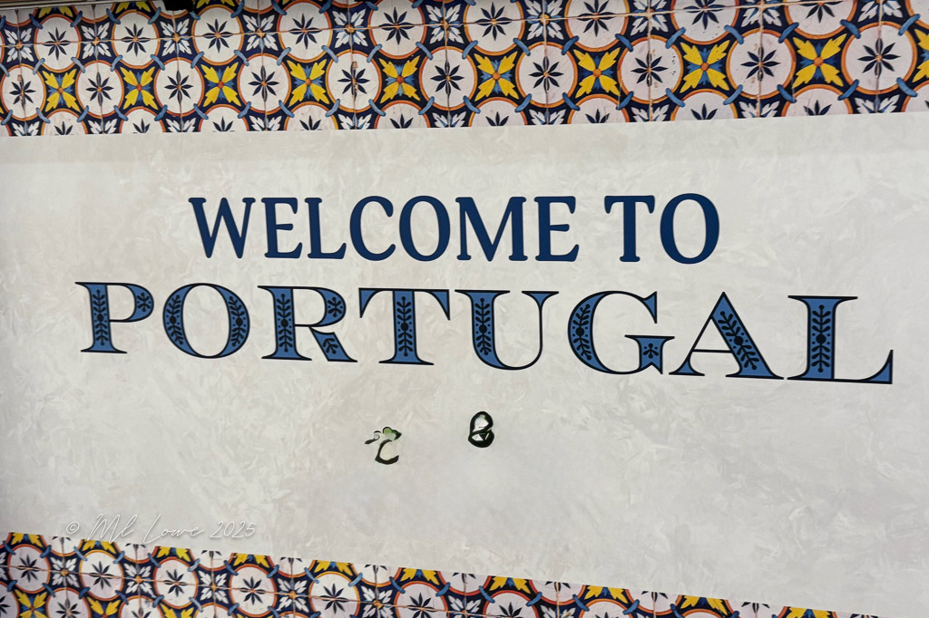 A decorative sign reading 'WELCOME TO PORTUGAL' against a colorful tiled background.