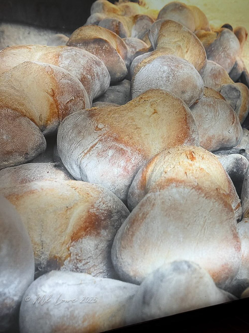 A close-up of traditional Portuguese bread known as 'Four Corners', featuring irregular shapes and a dusty, crusty exterior.