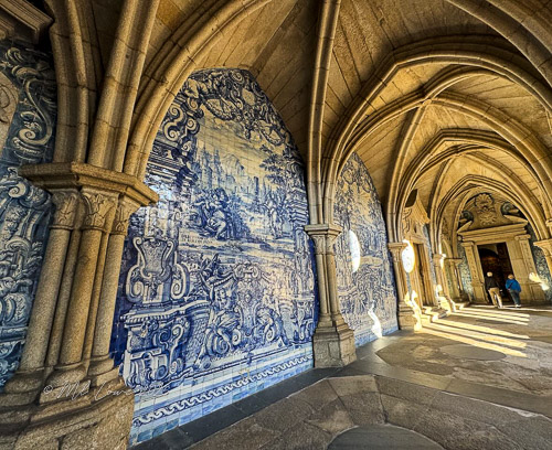 Interior of a historical building showcasing intricate blue and white azulejo tiles, with arches and soft lighting.