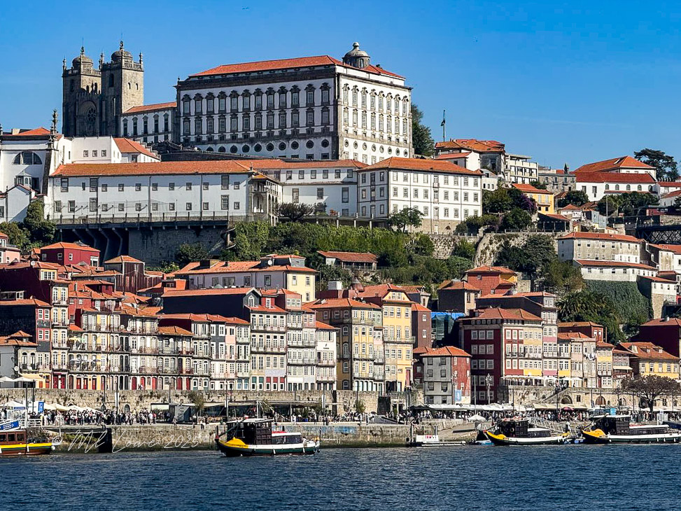A scenic view of Porto, Portugal, showcasing colorful buildings along the riverbank with historic architecture in the background.