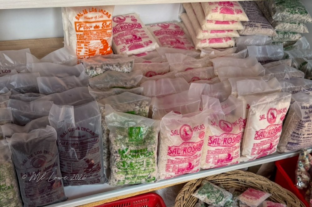 A display of various bags of salt and herbs on a wooden shelf, featuring colorful packaging with labels in Spanish.