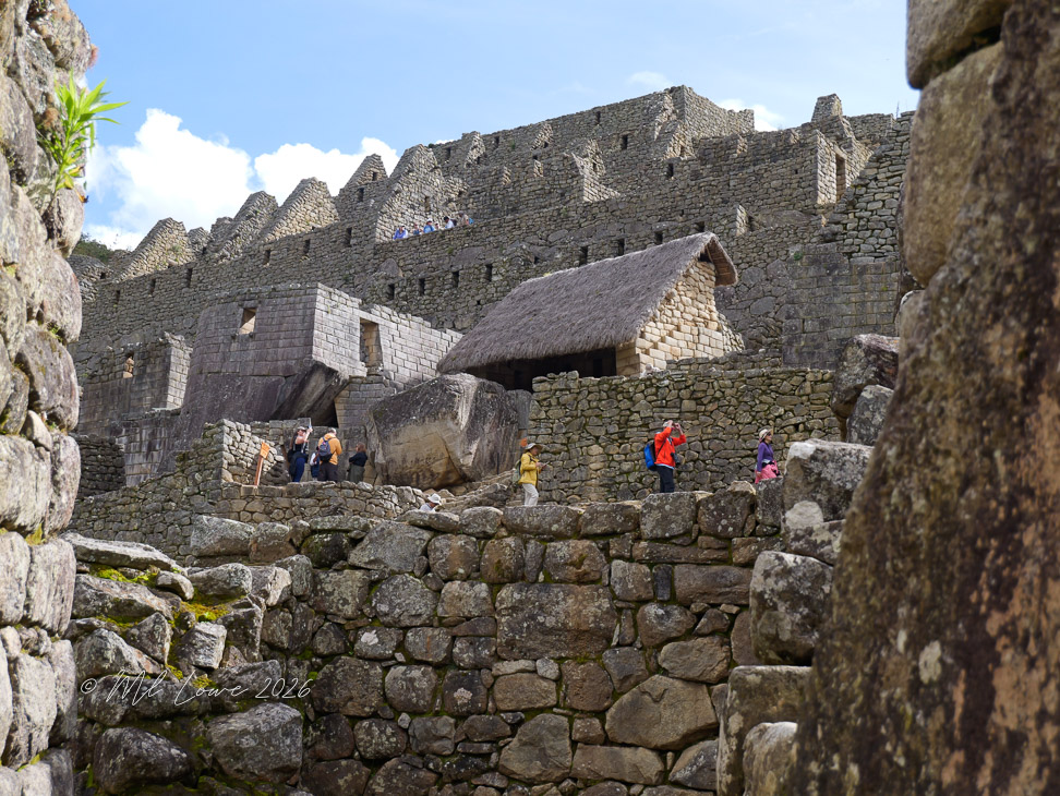 View of ancient stone structures and terraces at Machu Picchu, with tourists exploring the site.