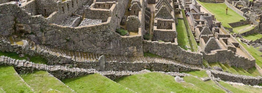 A panoramic view of the ancient ruins of Machu Picchu, highlighting stone structures and terraced gardens surrounded by lush green hills.